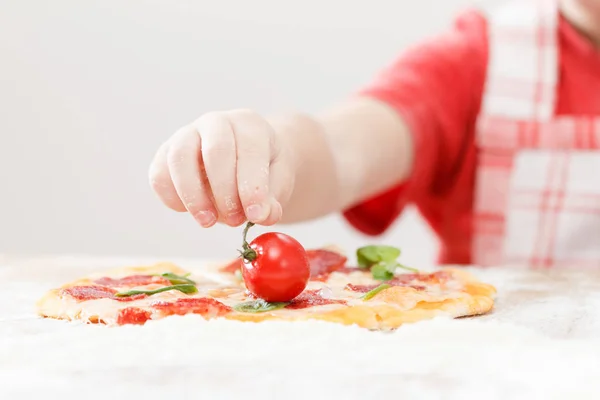 Koch legt Tomate über Mozzarella auf eine rohe Pizza — Stockfoto