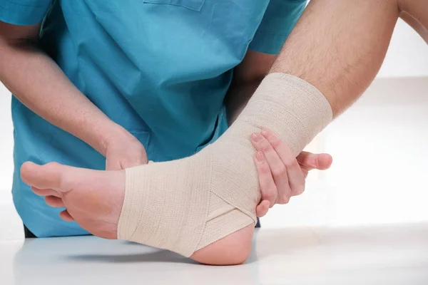 Primer plano del pie vendado médico masculino del paciente femenino — Foto de Stock
