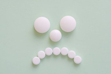 Yeşil Beyaz yuvarlak ilaçlarıyla yapılan üzgün hasta yüz