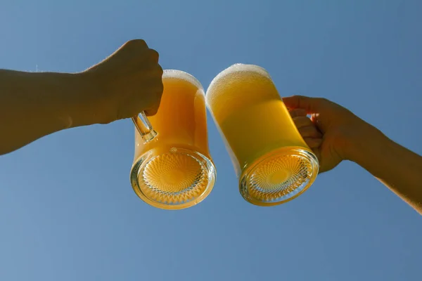 toasting with beers against clear blue sky