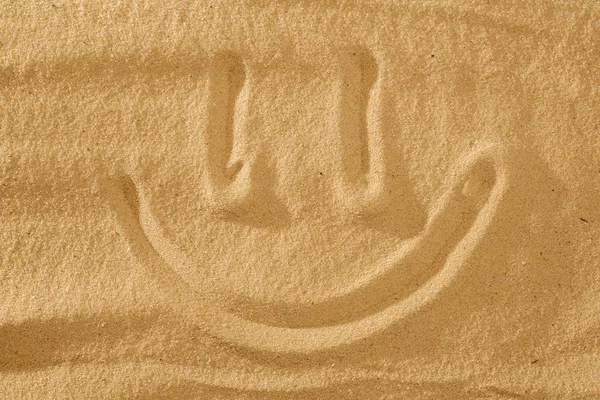 Visage manuscrit sur le sable de la plage. Symbole sourire sur fond de plage . — Photo