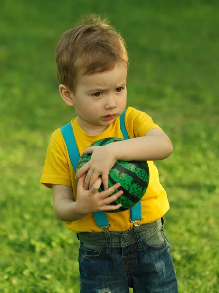Мила позитивна дитина, щасливо грає з м'ячем на зеленому лузі — стокове фото