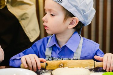 Pizzacı çubuk restoranda İtalyan pizza hazırlık Şef şapkalı çocuk. Hamur yoğurma ve germe