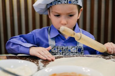 Pizzacı çubuk restoranda İtalyan pizza hazırlık Şef şapkalı çocuk. Hamur yoğurma ve germe