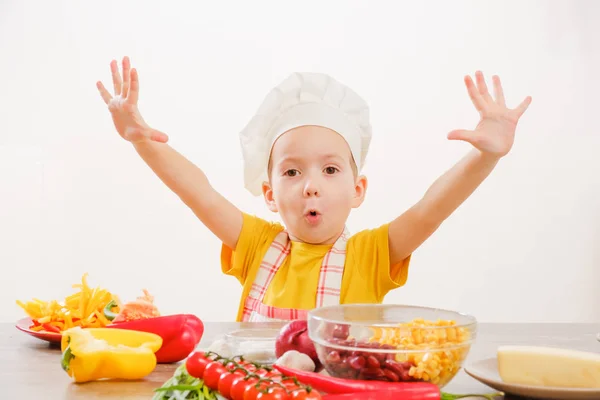 Happy child prepares and eats vegetables in kitchen