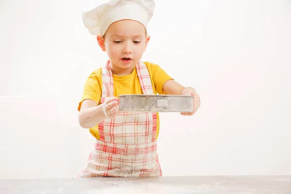 Mãos de crianças amassando a massa de farinha. cozinheiro alegre criança menino em boné prepara burritos — Fotografia de Stock