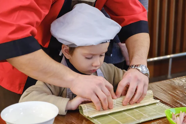 Cooking of traditional sushi rolls. The boy is dressed as a cook.
