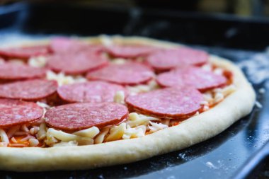 Taze İtalyan çiğ pizzası, geleneksel usulde fırında pişirme tepsisi üzerinde hazırlanma.