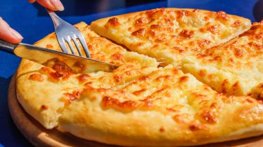 Dört peynirli pizza quattro fromaggi bir tahta masa, mavi arka plan üzerinde bıçak ile kesme