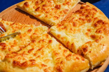 Dört peynirli pizza quattro fromaggi bir tahta masa, mavi arka plan üzerinde bıçak ile kesme