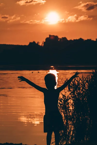 Boy on sunset background over summer river. — Stock Photo, Image
