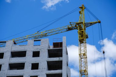 Mavi gökyüzüne karşı inşaat vinci ve bina