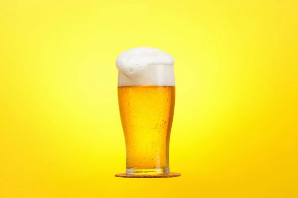 Vaso de cerveza en primer plano con espuma sobre fondo amarillo —  Fotos de Stock
