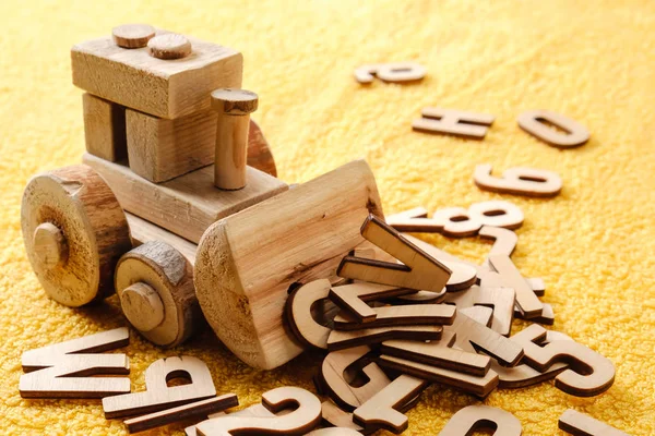 Letras del alfabeto de madera con juguete. Concepto educativo sobre fondo amarillo —  Fotos de Stock
