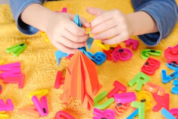 Pequeña mano de bebé jugando con coloridos juguetes y letras —  Fotos de Stock
