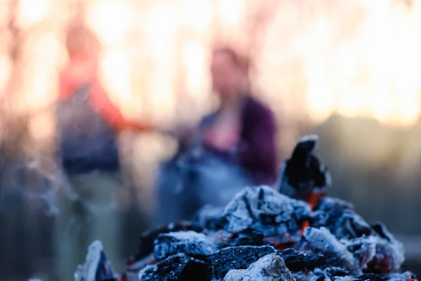 Mother and son sit in the evening at the fire at a picnic