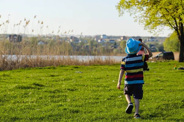 Niño caucásico feliz corriendo en la hierba del prado, verano en el parque natural — Foto de Stock