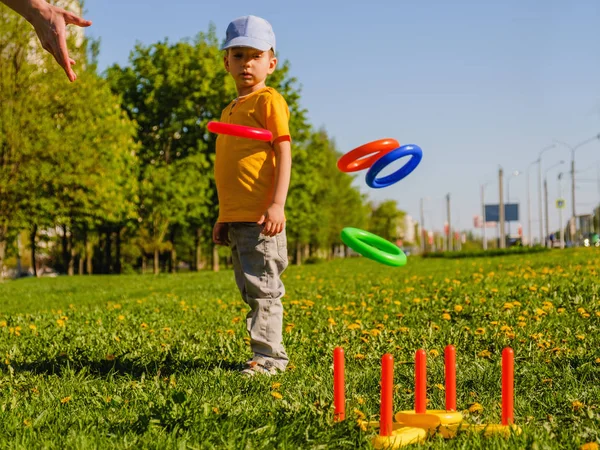Menino a brincar. Anel jogar jogo de verão em um gramado verde ao sol — Fotografia de Stock