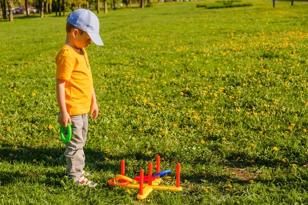 Niño jugando. Anillo de lanzar juego de verano en un césped verde en el sol — Foto de Stock