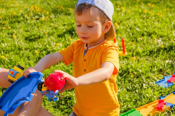 Chico juega con un coche de juguete en el césped verde . — Foto de Stock