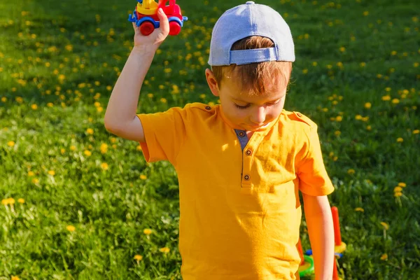 Junge spielt mit Spielzeugauto auf dem grünen Rasen. — Stockfoto