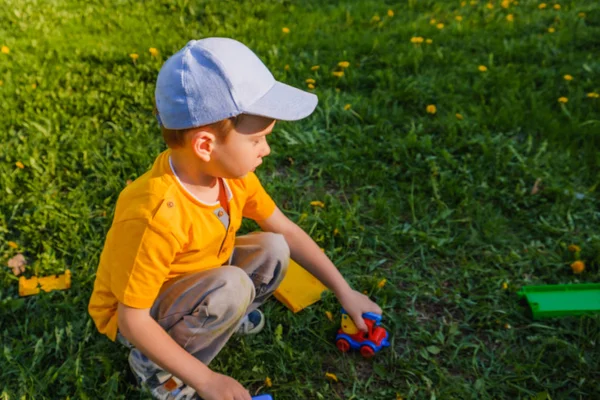 Junge spielt mit Spielzeugauto auf dem grünen Rasen. — Stockfoto