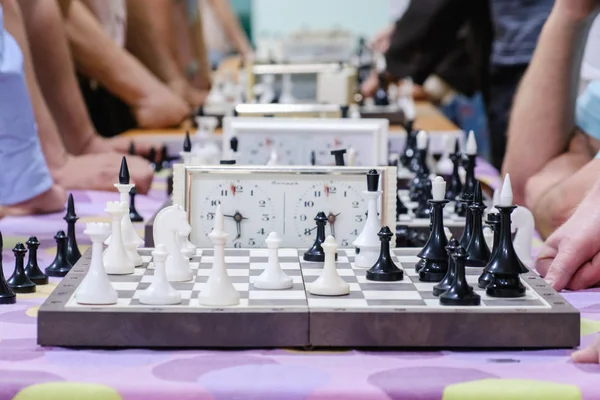 Шахматная доска с фигурами и часами на деревянном столе в связи с шахматным турниром . — стоковое фото