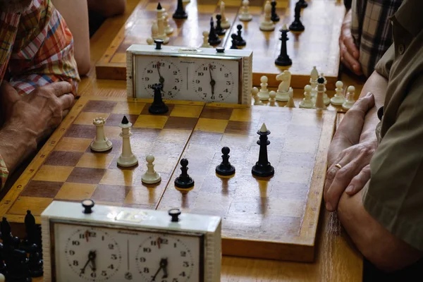 Schachbrett mit Figuren und Uhr auf Holztisch in Verbindung mit dem Schachturnier. — Stockfoto