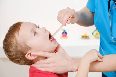 Doktor grip belirtileri nedeniyle beyaz çocuğun boğazına bakıyor.