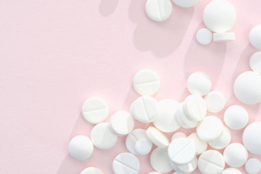 Pembe arka planda beyaz haplar yığını, soyut olarak kapat