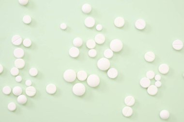 Yeşil zemin üzerinde beyaz haplar yığını, soyut yakın çekim