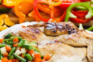 Arka plandaki ızgarada kabuklu tavuk pişirme biberi ve sebze.