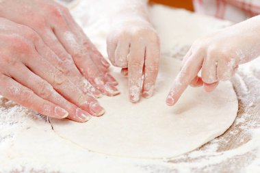 Anne ve çocuk elleri hamuru un, merdane ve buğday ile yukarıdan kırsal ahşap masa üzerinde hazırlar. Ekmek ya da pizza için ev yapımı pasta. Fırın arka planı.