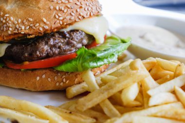 Hamburger ve patates kızartması masada beyaz tabakta..