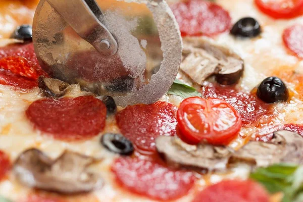 Biberli pizzayı özel bıçakla dilimlemek. Eline bıçak al..