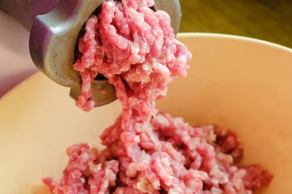 Close up of front part meat grinder or mincing-machine with mincemeat in. Showing the forcemeat process.