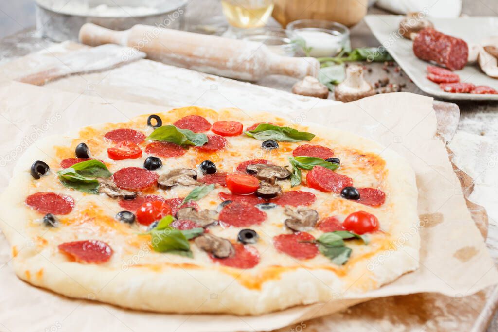 Assorted pizza with different fillings salamy, mushrooms served on wooden table with ingredients mushrooms, salami, peperoni, tomatoes, cheese