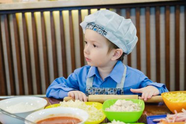 Aşçı şapkalı çocuk İtalyan yemeği pişiriyor, mutlu..