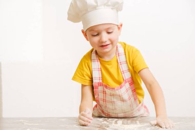 Çocukların ellerinin hamur yoğuruşuyla ilgili detaylar. Neşeli aşçı şapkalı çocuk burrito ya da pizza hazırlar.