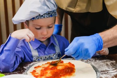Şef şapkalı çocuk pizza pişiriyor İtalyan yemeği, beyaz kafe..