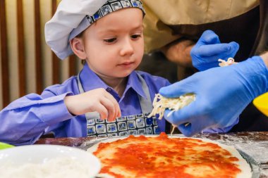 Aşçı şapkalı çocuk İtalyan yemeği pişiriyor, peynir pişiriyor..