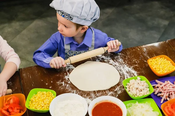 Kid in chef hat cooking pizza italian food,  kitchen cafe.