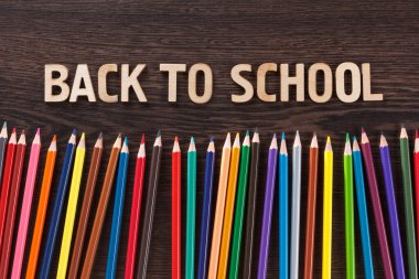 Koyu ahşap arka planda renkli kalem boyaları, okula dönüş.