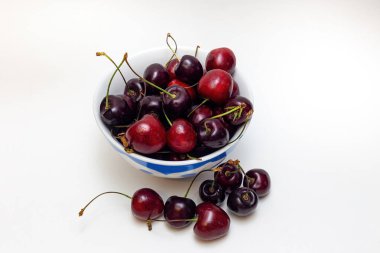 Tabakta beyaz bir zemin üzerinde siyah kirazlar.