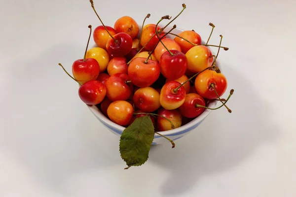 Yellow-red cherries on a white background in a plate.