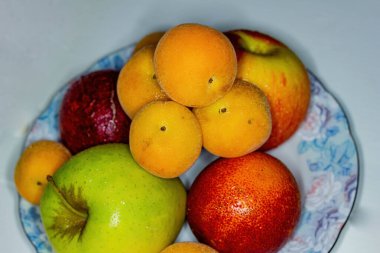 Beyaz bir arka planda, olgun kayısılar ve diğer meyvelerle dolu bir hayat.