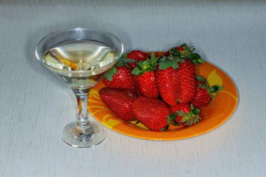 Beyaz arka planda bir bardak şaraplı çilek..