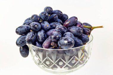  Vazoda tatlı siyah üzümler ve beyaz arka planda su damlaları var..