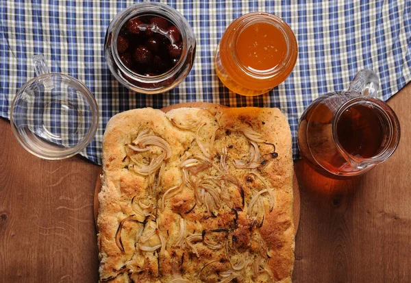 Focaccia, té, miel, mermelada en la mesa de madera con mantel a cuadros. Vista superior —  Fotos de Stock