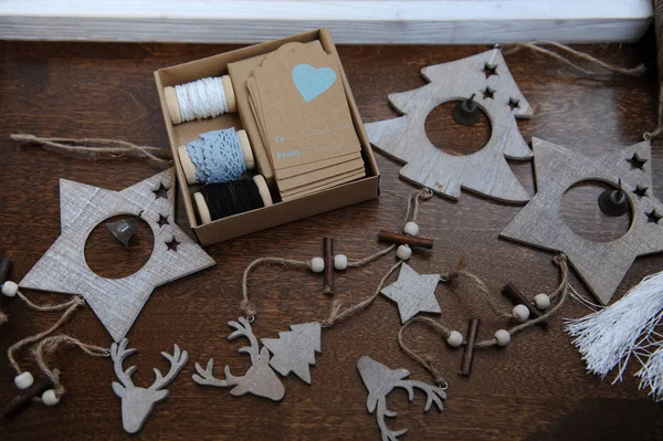Ξύλινες χειροποίητες διακοσμήσεις Χριστουγέννων. Το κεφάλι ενός ελαφιού, χριστουγεννιάτικα δέντρα και τα αστέρια. Κραφτ κουτί με κορδέλες σε καρούλια και συγχαρητήριο Ετικέτες — Φωτογραφία Αρχείου